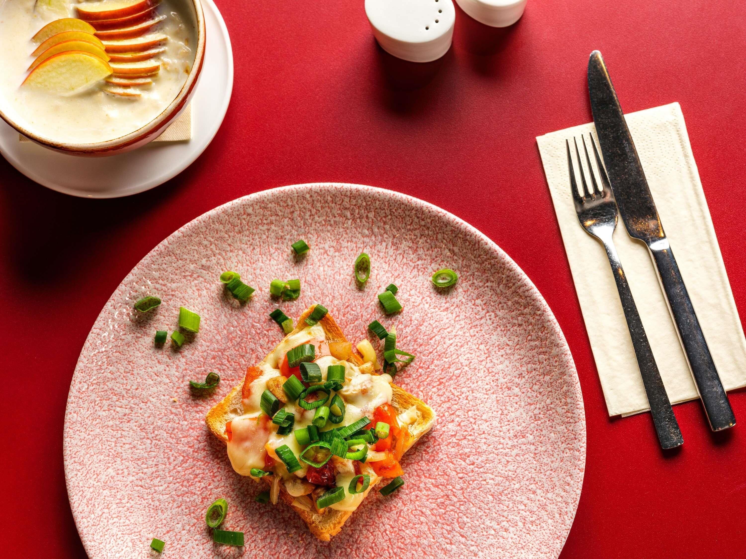A plate of food with a knife and fork on a red table.