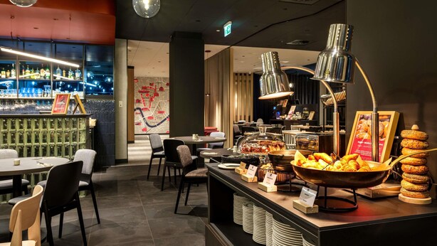 A restaurant with a bar area, seating, and a buffet with various food items. - ibis Krakow Centrum (Kraków)