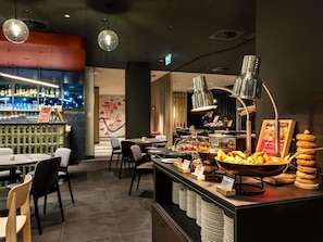 A restaurant with a bar area, seating, and a buffet with various food items. - ibis Krakow Centrum (Kraków)