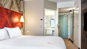 Una habitación de hotel con cama, baño con espejo y televisor.