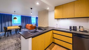 A modern kitchen with wooden cabinets, a black countertop, and a built-in dishwasher. - ibis Krakow Centrum (Kraków)