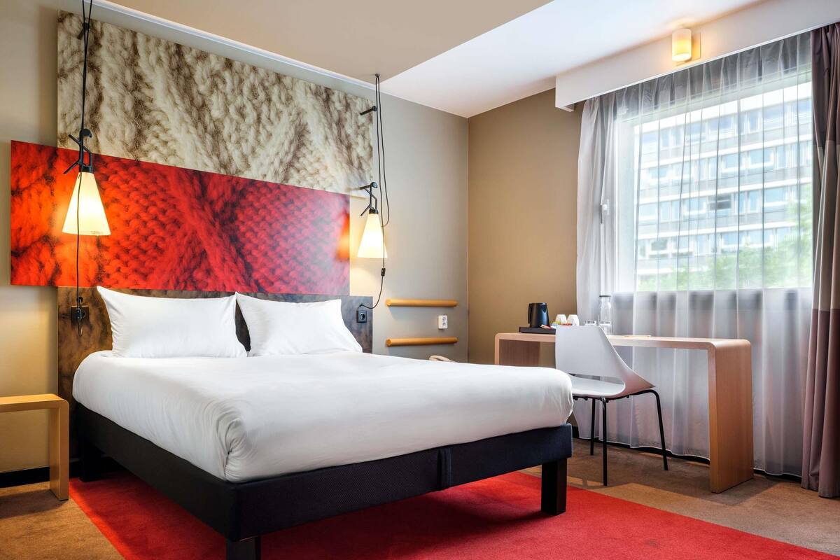 Une chambre d’hôtel avec un lit, un bureau et une fenêtre.