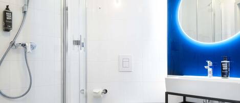 Un baño moderno con cabina de ducha de vidrio, inodoro, lavabo con espejo y toallero.