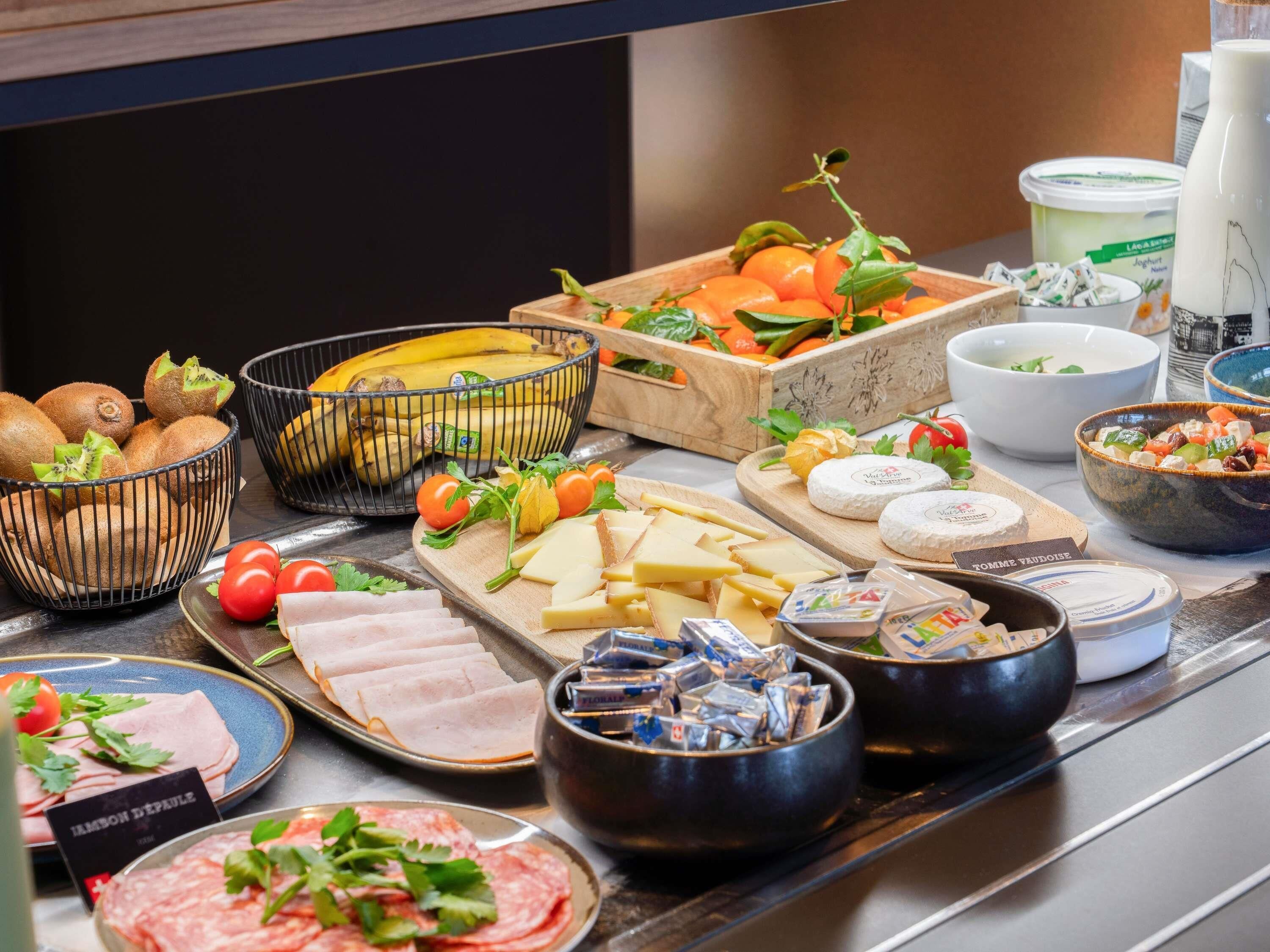 A buffet with various food items including fruits, cheeses, meats, and condiments.