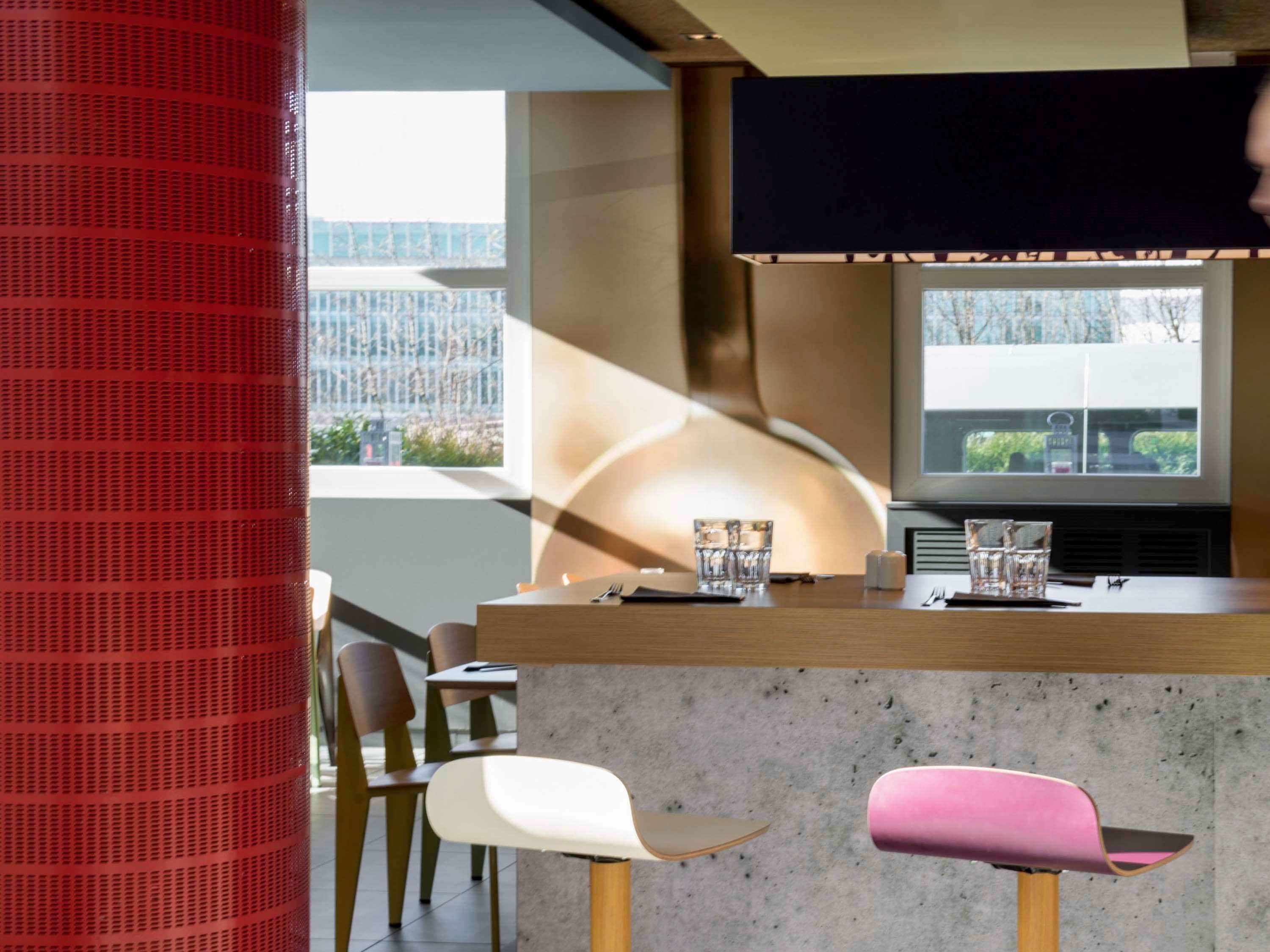 Eine moderne Bar mit einer Theke, Barhocker und einem großen Fenster mit Blick auf die Stadtlandschaft.