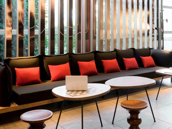A modern seating area with a sofa and round tables, featuring a laptop on one of the tables.