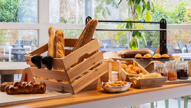 A buffet table with bread, pastries, and condiments. - ibis Geneve Aeroport (Meyrin)