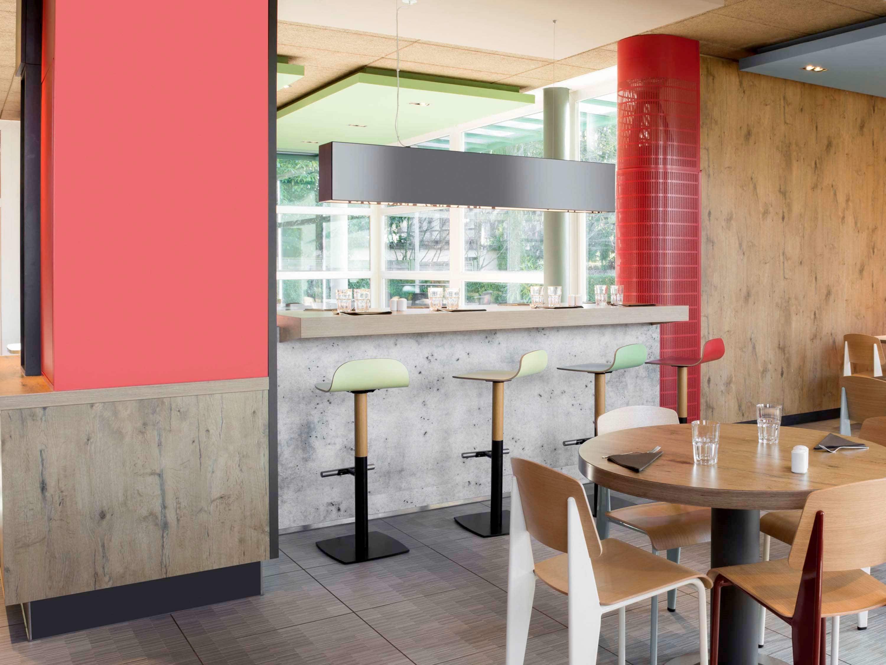 Un interior de restaurante moderno con una zona de bar, taburetes altos y una mesa redonda para comer.