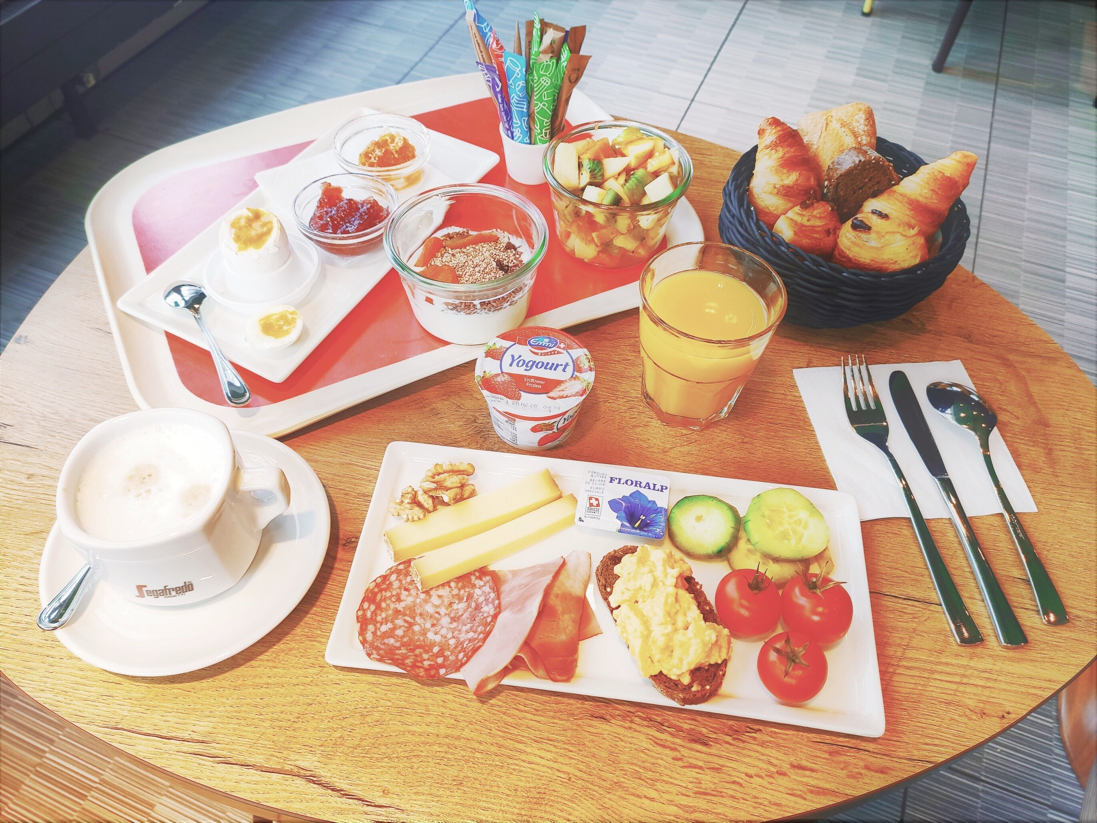 A breakfast tray with various foods and drinks, including toast, eggs, tomatoes, and a glass of orange juice.