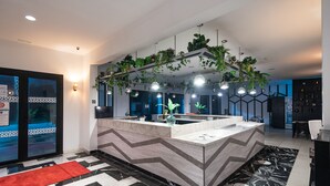 A modern kitchen with a central island, pendant lighting, and hanging plants. - ibis Meknes Hotel (Meknes)
