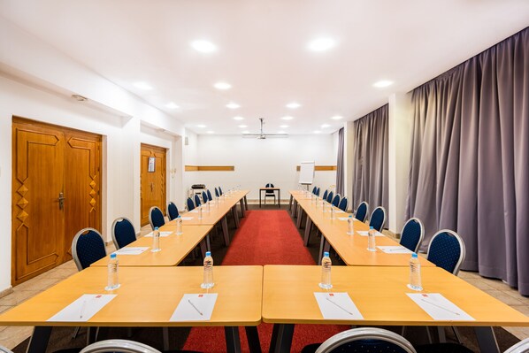 A conference room with long tables, chairs, and a red carpet. - ibis Meknes Hotel (Meknes)