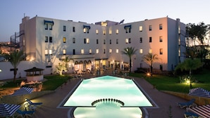 A hotel with a swimming pool, outdoor seating, and a well-lit courtyard. - ibis Meknes Hotel (Meknes)