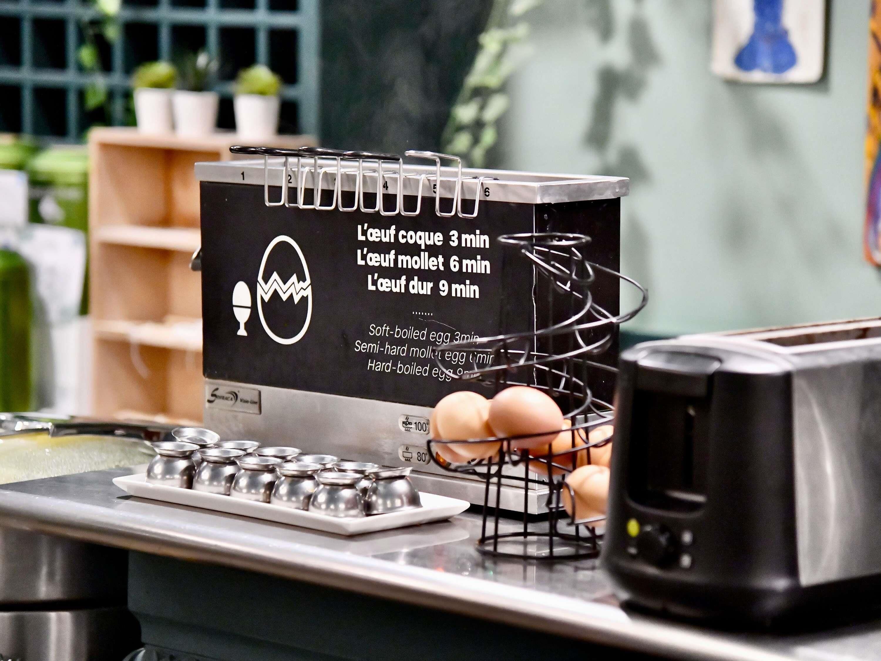 A kitchen counter with a cooking guide, a wire rack with eggs, and a stove.