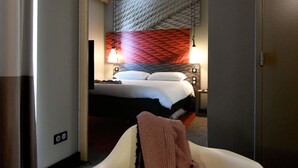 Ein Hotelzimmer mit einem Bett, einem Nachttisch, einer Lampe und einer roten Wand mit Muster.