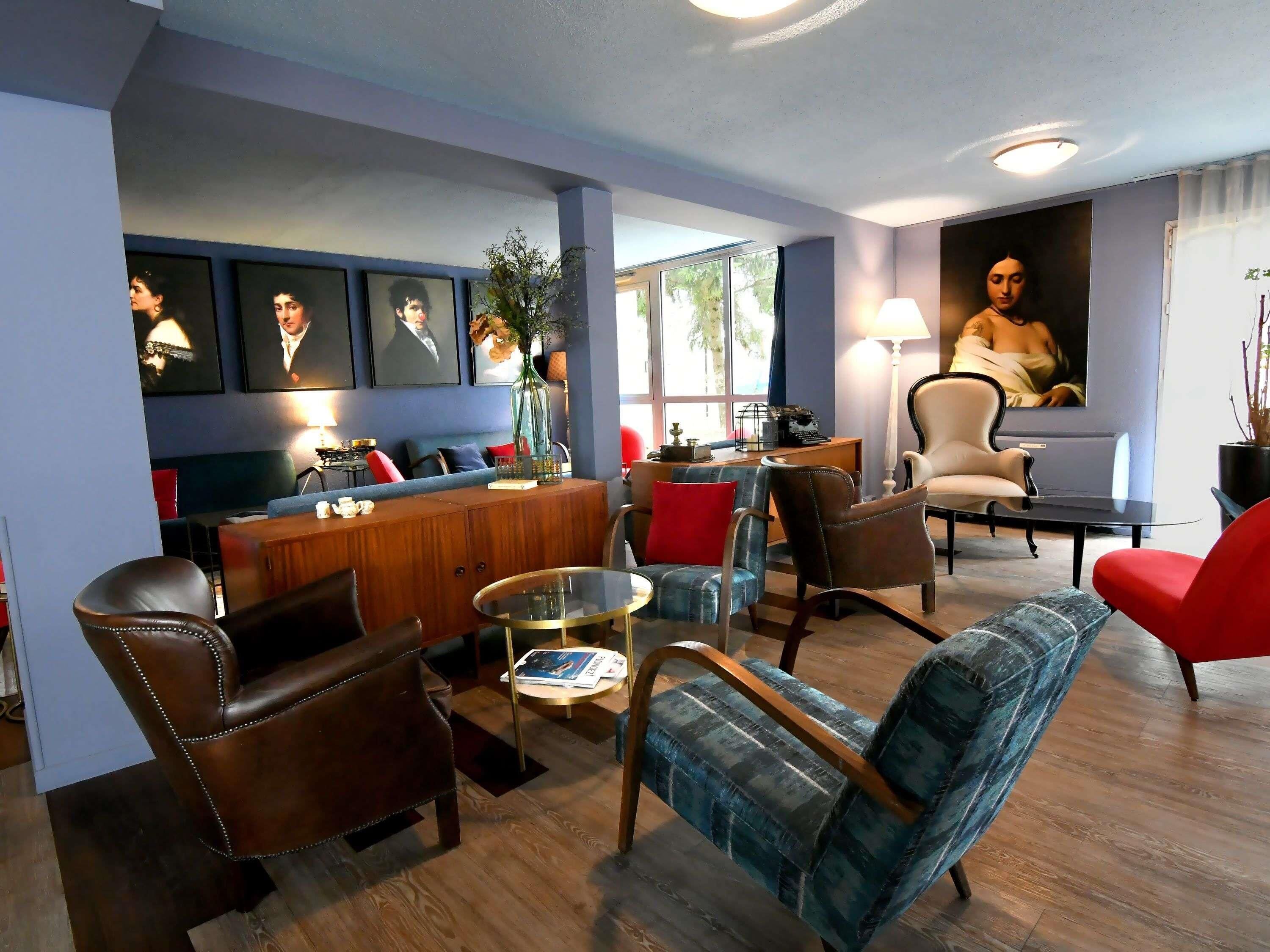 A modern living room with a bar area, leather chairs, a glass coffee table, and artwork on the walls.