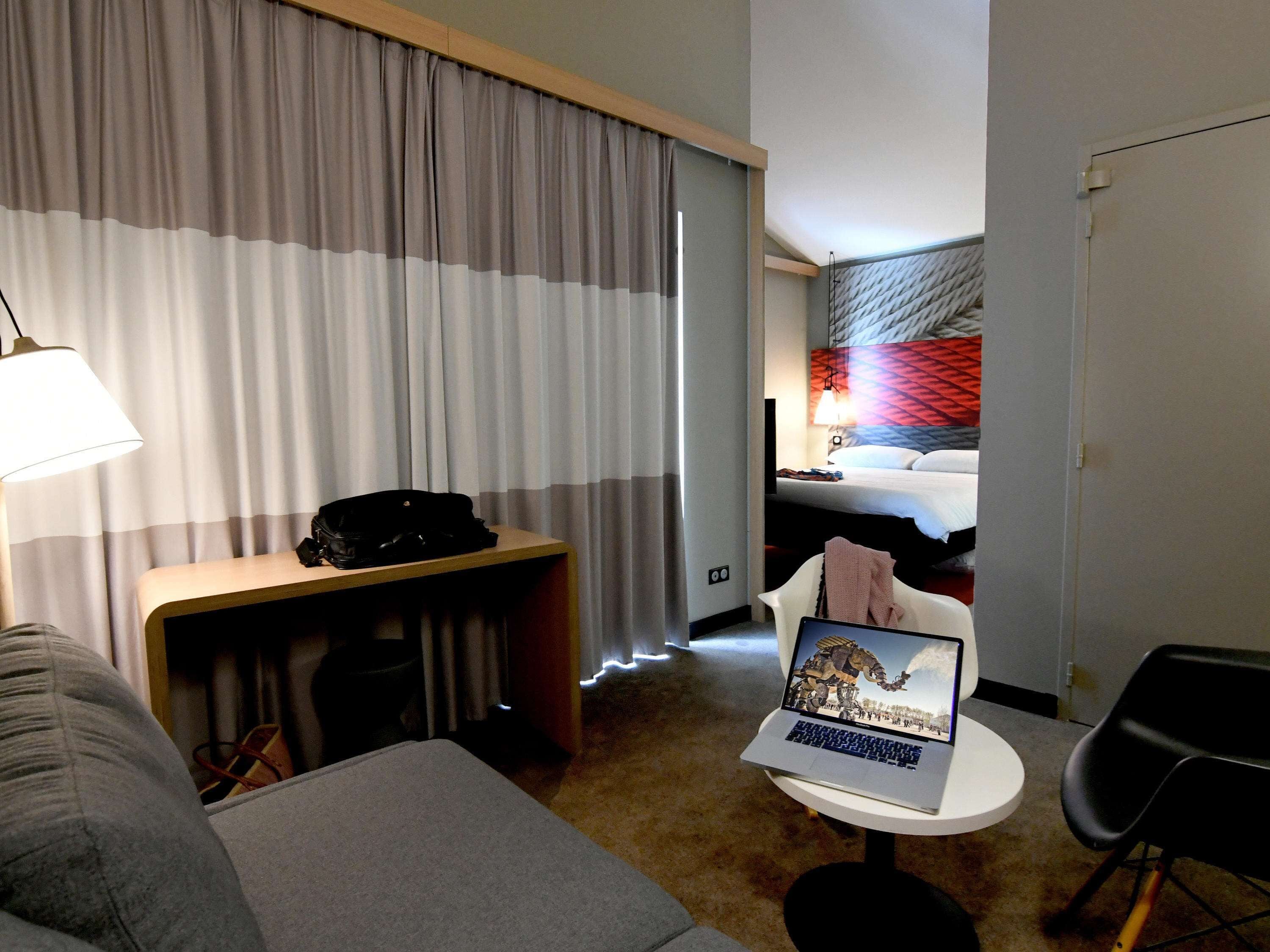 A hotel room with a bed, a desk with a laptop, a chair, and a couch.