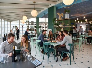 Een restaurant met tafels, stoelen en mensen aan het dineren.