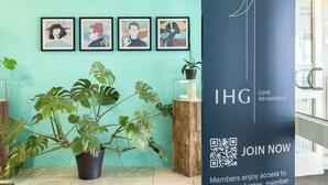 A reception area with framed artwork on the wall, a potted plant, and a sign promoting a rewards program.