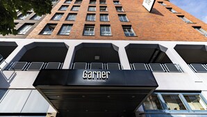 A hotel entrance with a modern facade, large windows, and a prominent sign for 'Garnier An IHG Hotel'.