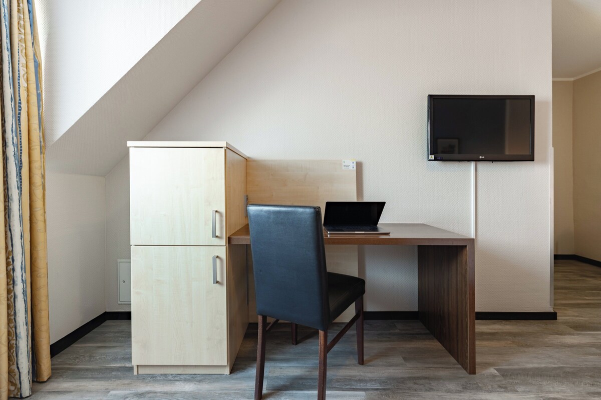 Una habitación pequeña y moderna con escritorio, silla y televisor montado en la pared.