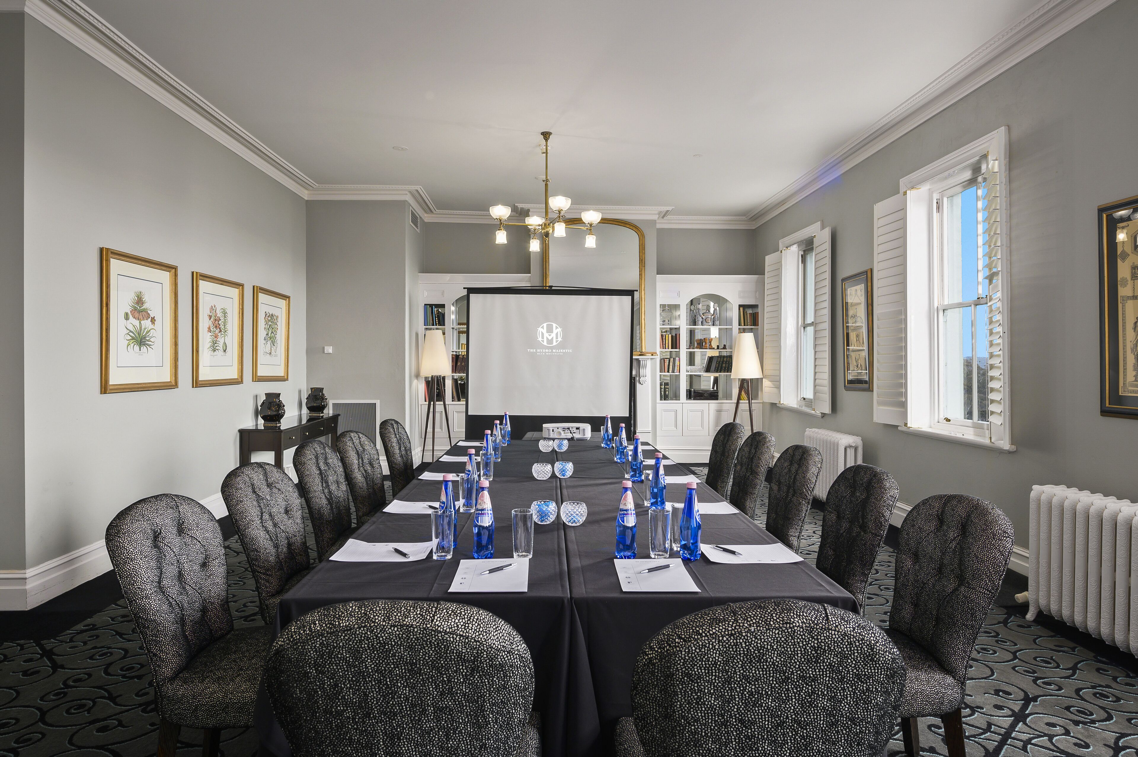 A conference room with a long table, chairs, and a projector screen.