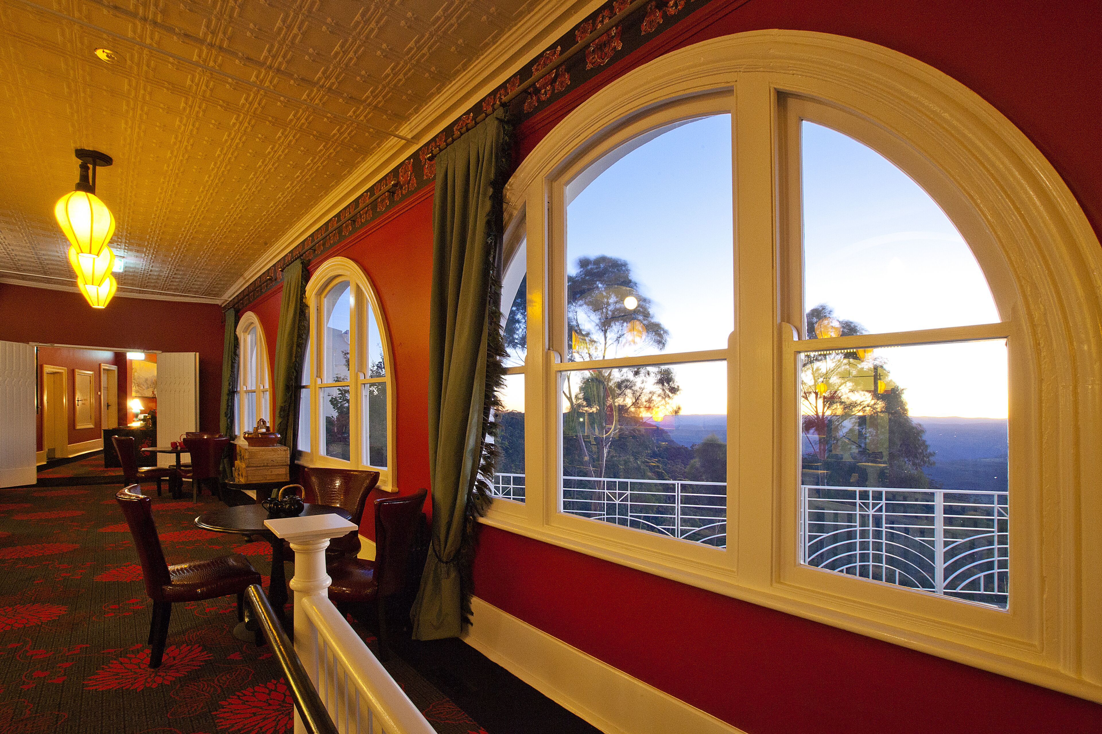 A hotel room with large arched windows, a red carpet, and a chandelier.