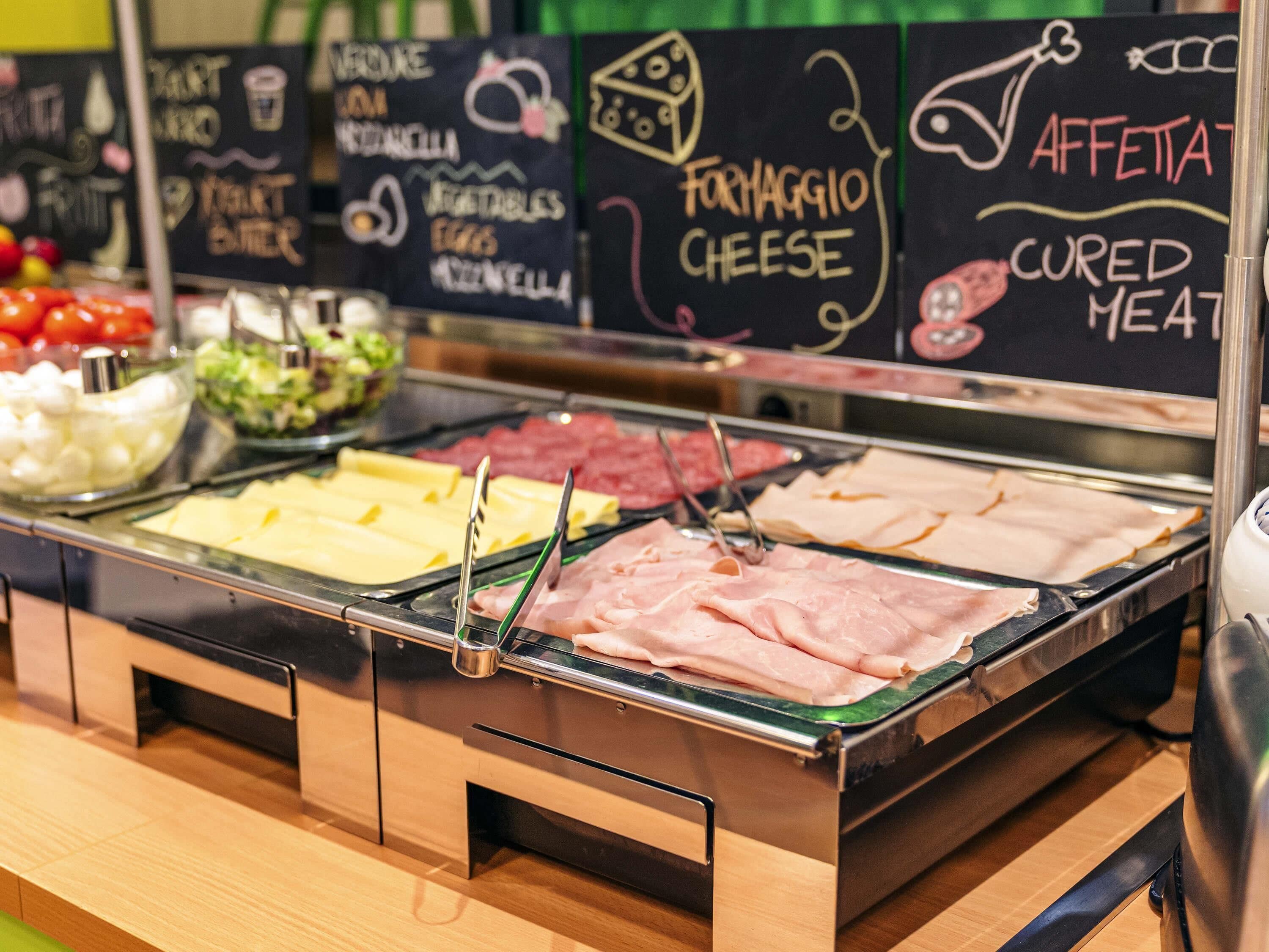 A buffet with various food options including cheese, cured meats, and vegetables.