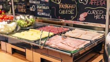 A buffet with various food options including cheese, cured meats, and vegetables.