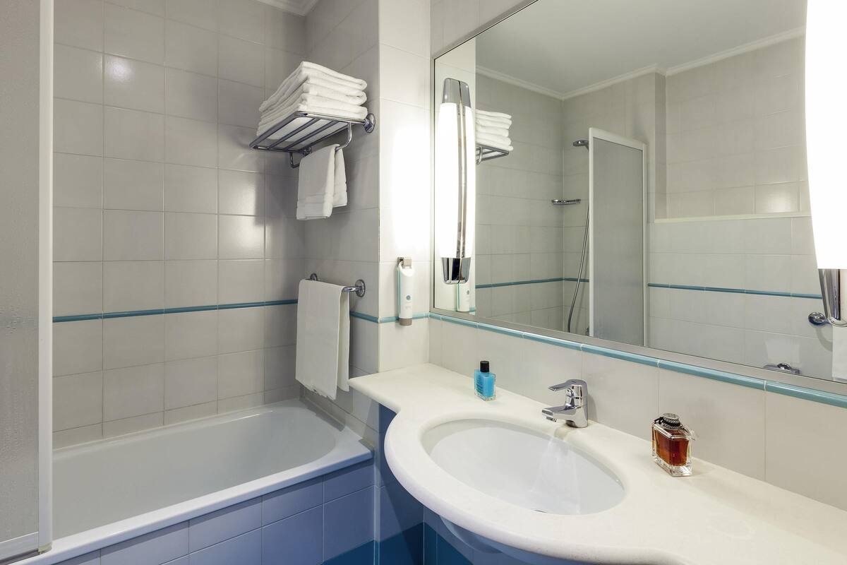 A modern bathroom with a bathtub, a sink, and a large mirror.