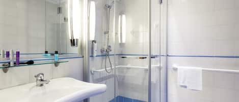 Une salle de bain moderne avec une douche en verre, un lavabo blanc et un sol carrelé de carreaux bleus.