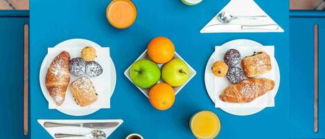 Una mesa con fuentes de pasteles, frutas y bebidas.
