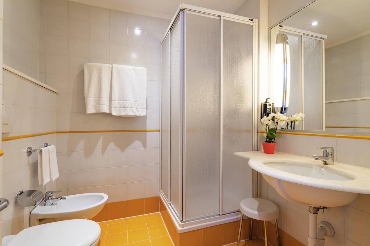 Une salle de bain avec une douche, deux lavabos, des toilettes et un miroir.