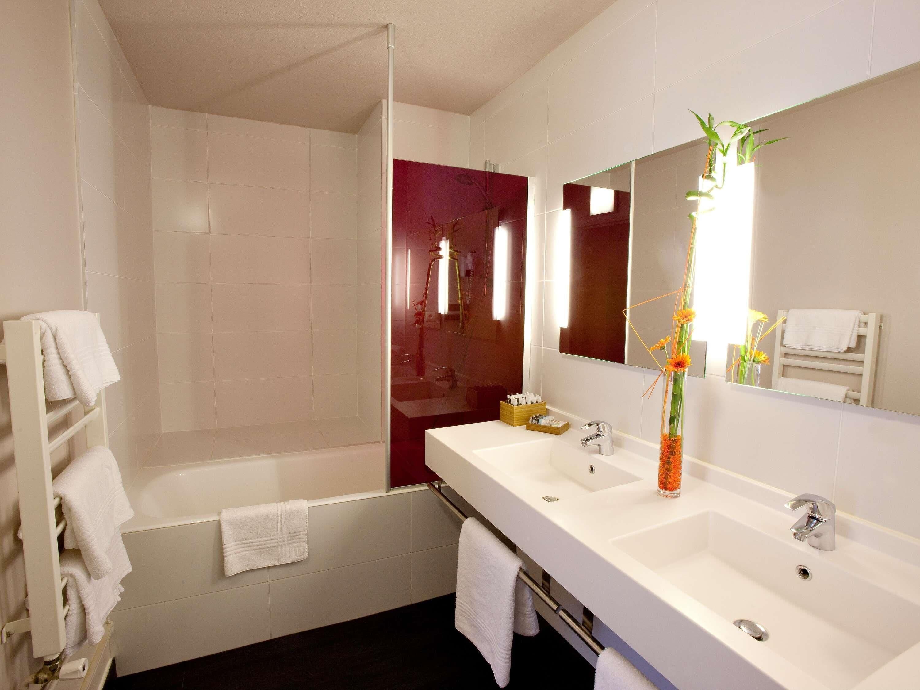 A modern bathroom with a shower, a large mirror, a sink, and a towel rack.