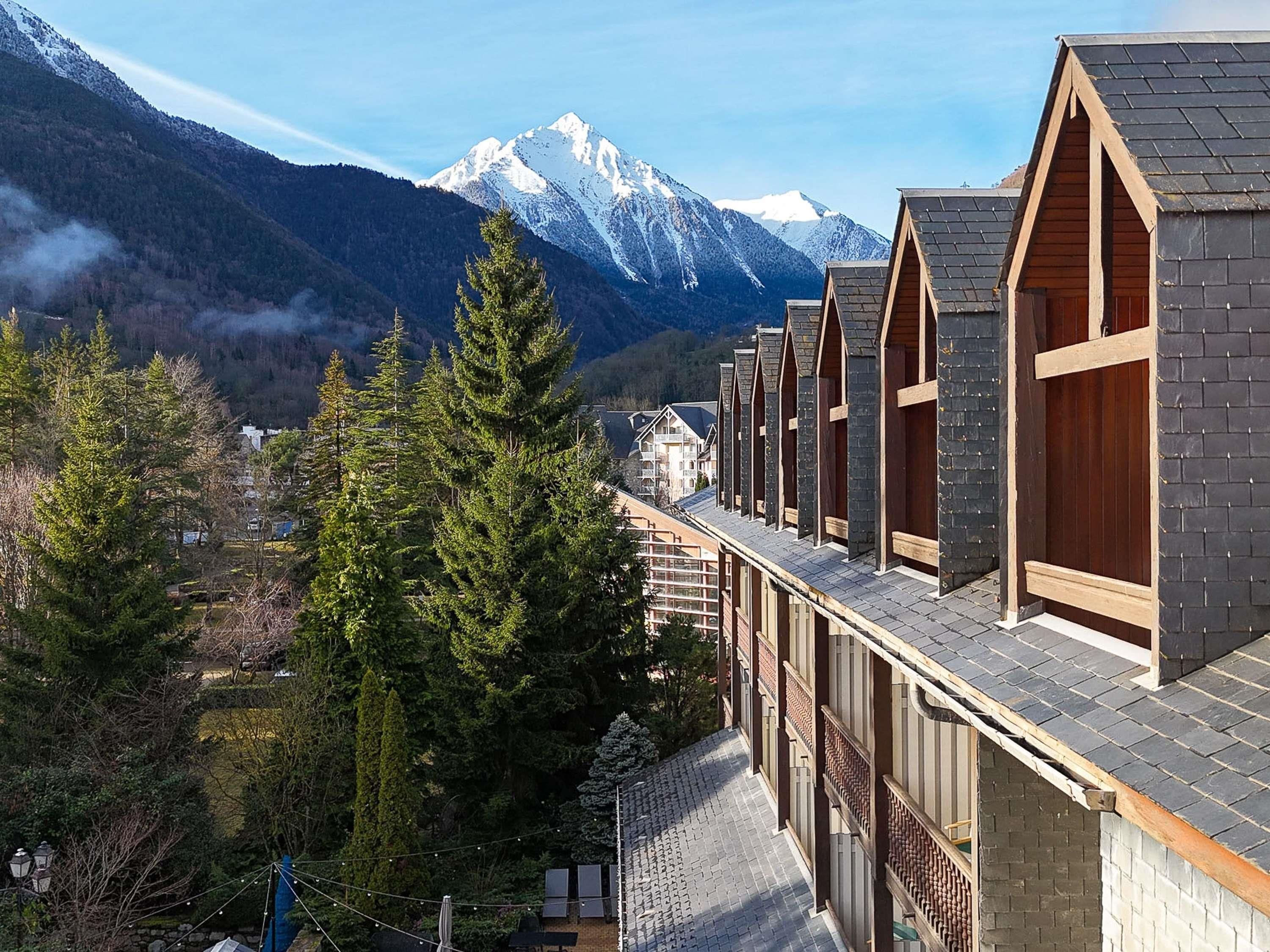 A row of chalet-style buildings with a mountain backdrop.