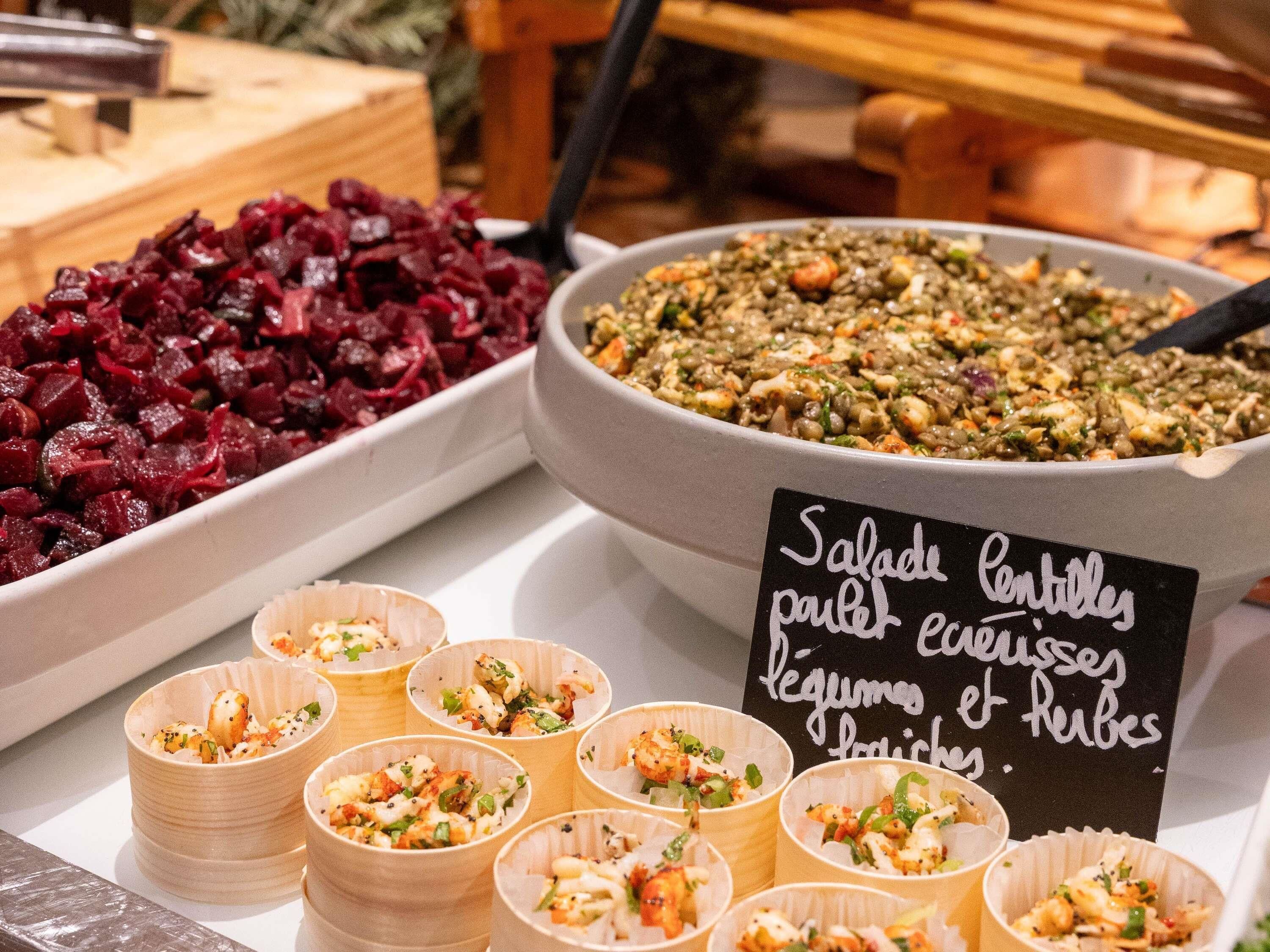 A buffet with various dishes including beetroot salad, lentil salad, and seafood cups.