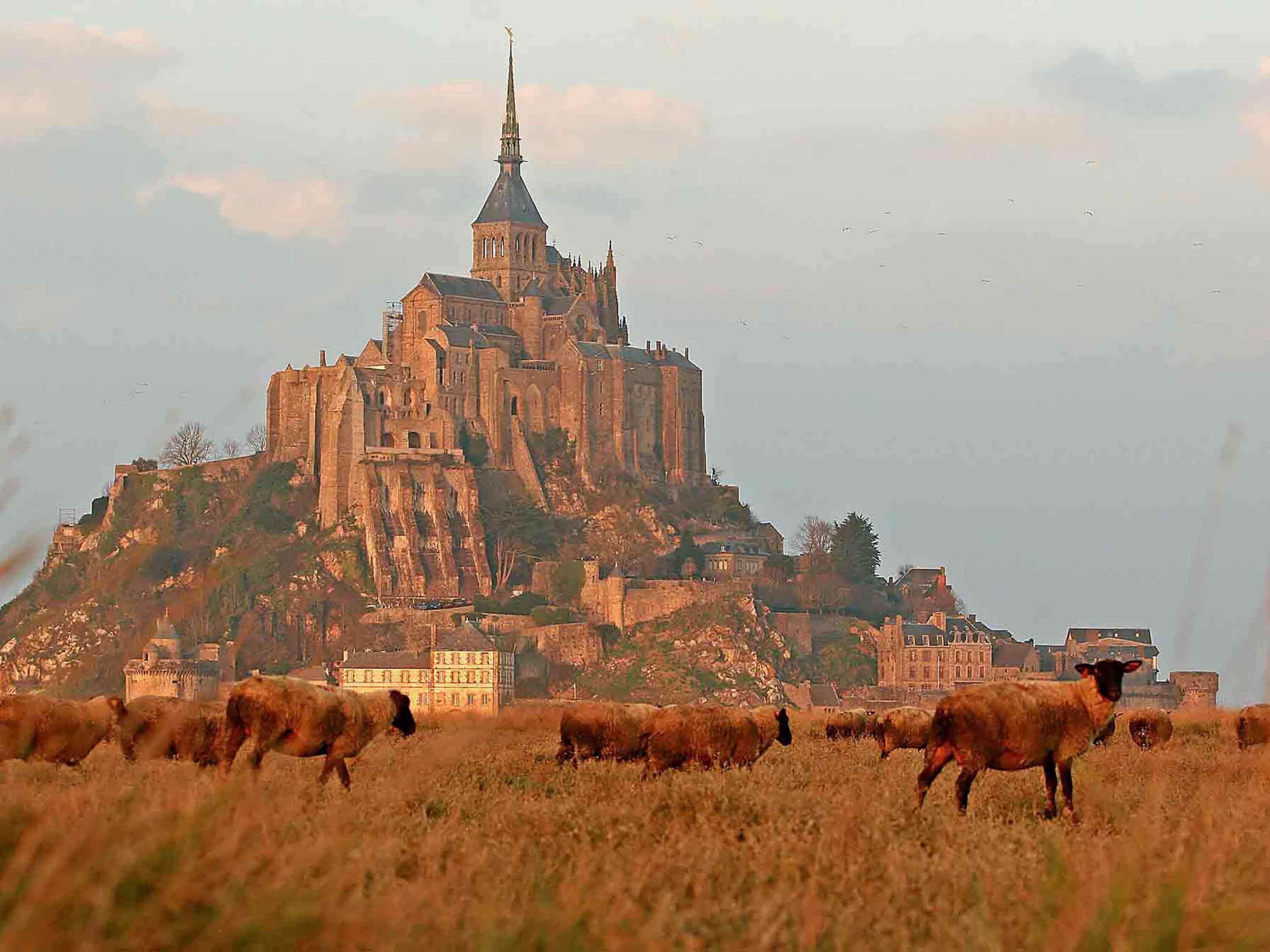 A historic castle with a prominent tower and a large building in the foreground.