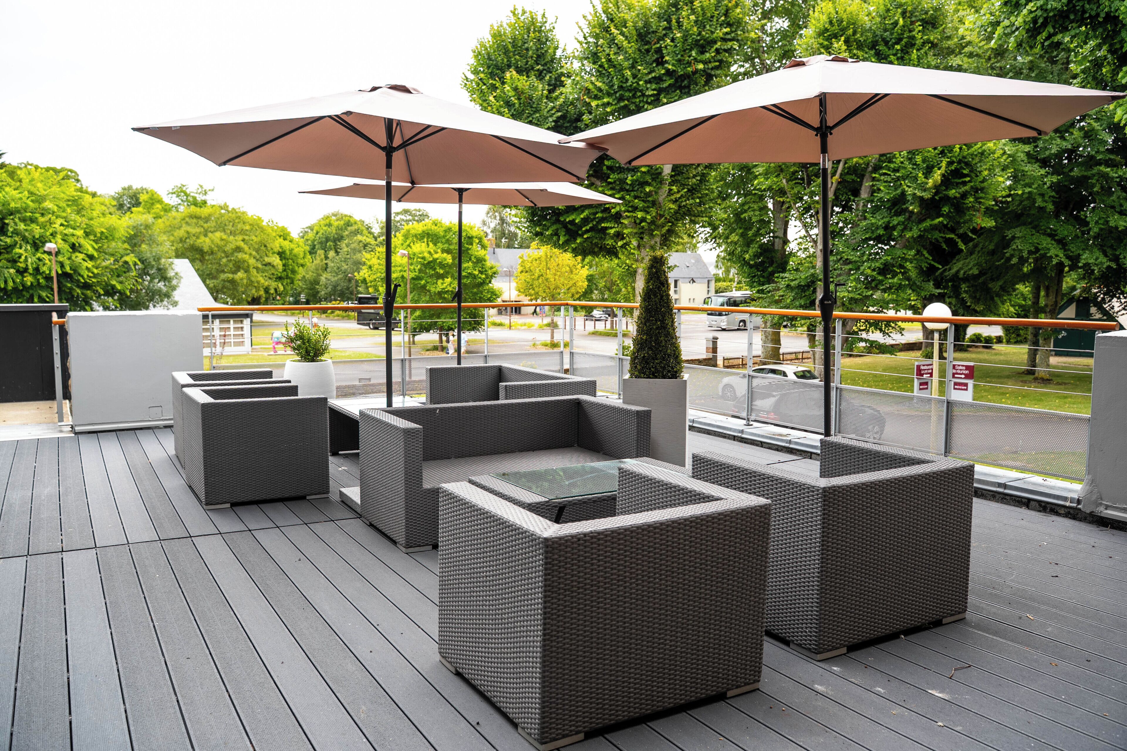 Een terras met rieten meubels en grote parasols.