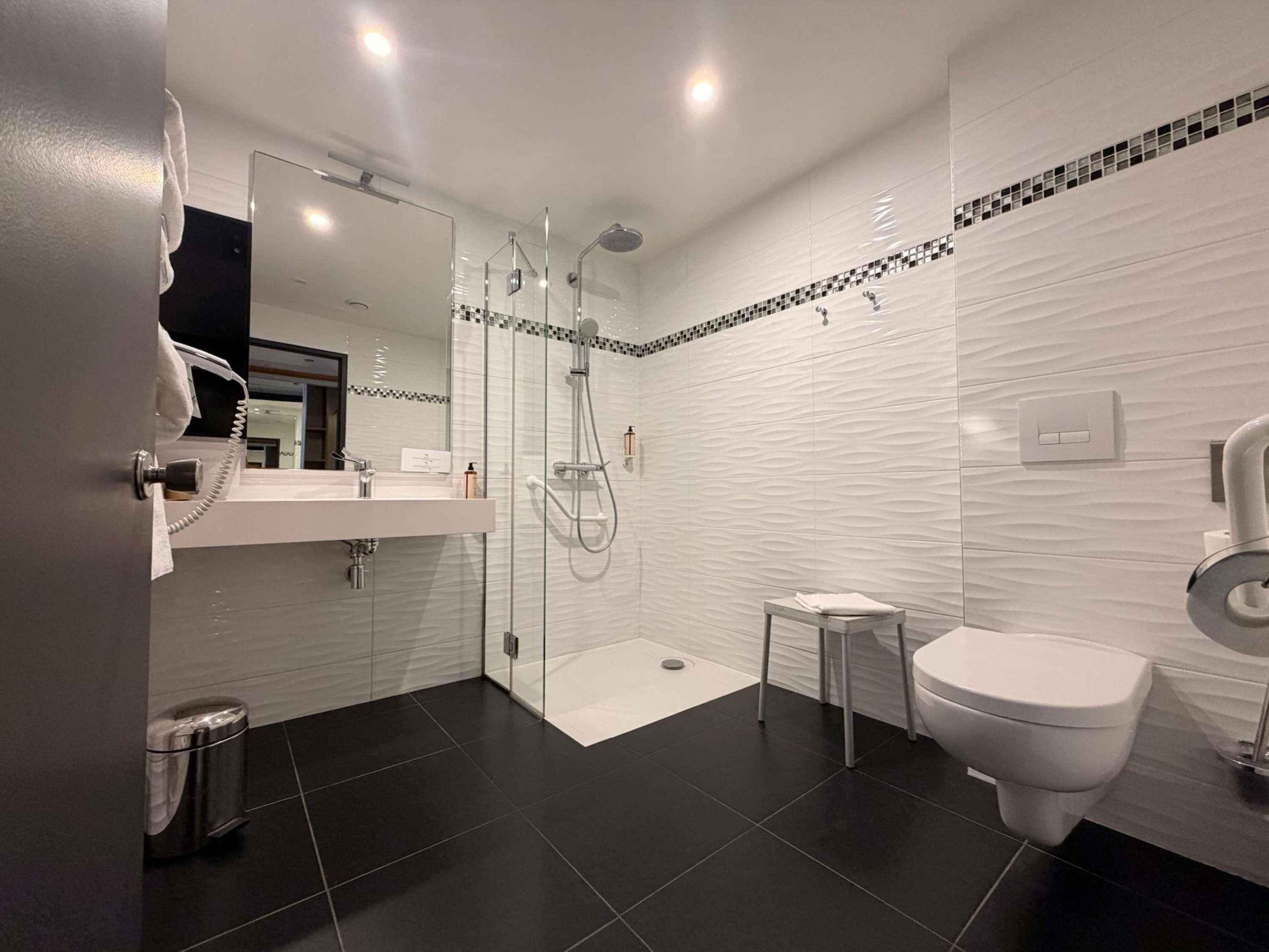 A modern bathroom with a glass-enclosed shower, a toilet, and a sink.