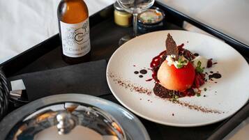 A dessert plate with a chocolate dessert, a bottle of Cidre Brut, and a glass of white wine on a tray.