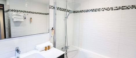 A modern bathroom with a white sink, a glass-enclosed shower, and a large mirror.