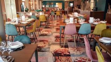En restaurang med flera bord och stolar, en mönstrad matta och en modern takdesign.