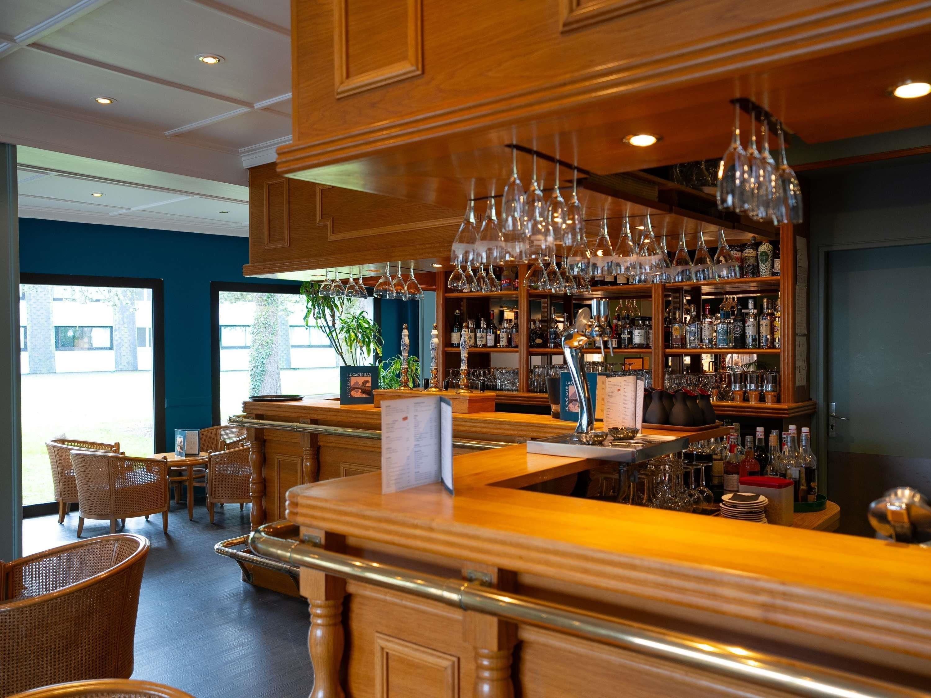 A bar area with wooden furniture, hanging wine glasses, and a variety of bottles.