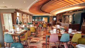 Ein Restaurant mit mehreren Tischen, bunten Stühlen und einem außergewöhnlichen Deckengestalt.