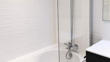 A modern bathroom with a glass-enclosed shower, a white bathtub, and a black vanity.