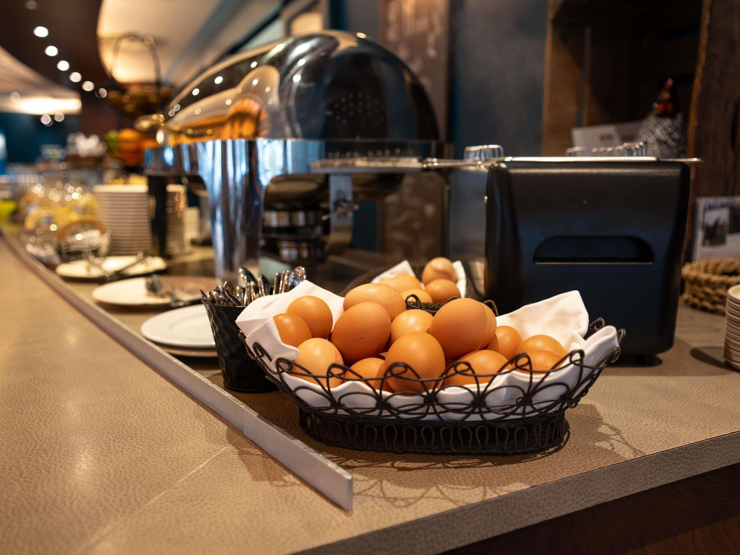 A breakfast buffet with eggs, utensils, and a coffee machine.