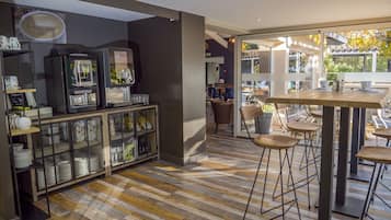 Un café moderne doté d’un bar, d’un plancher en bois et offrant une vue sur l’extérieur.