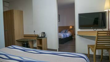 Une chambre d’hôtel équipée d’un lit, d’un bureau, d’une télévision et d’une armoire.