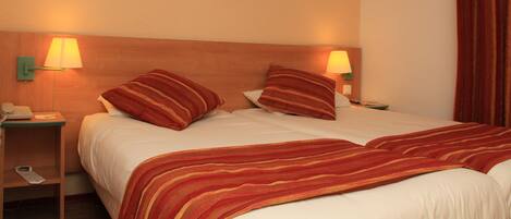 Habitación de hotel con cama, dos lámparas de noche, una mesita de noche y un cuadro en la pared.