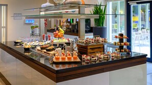 A buffet with various food items and a glass display case with decorative items. - Novotel Köln City (Cologne)