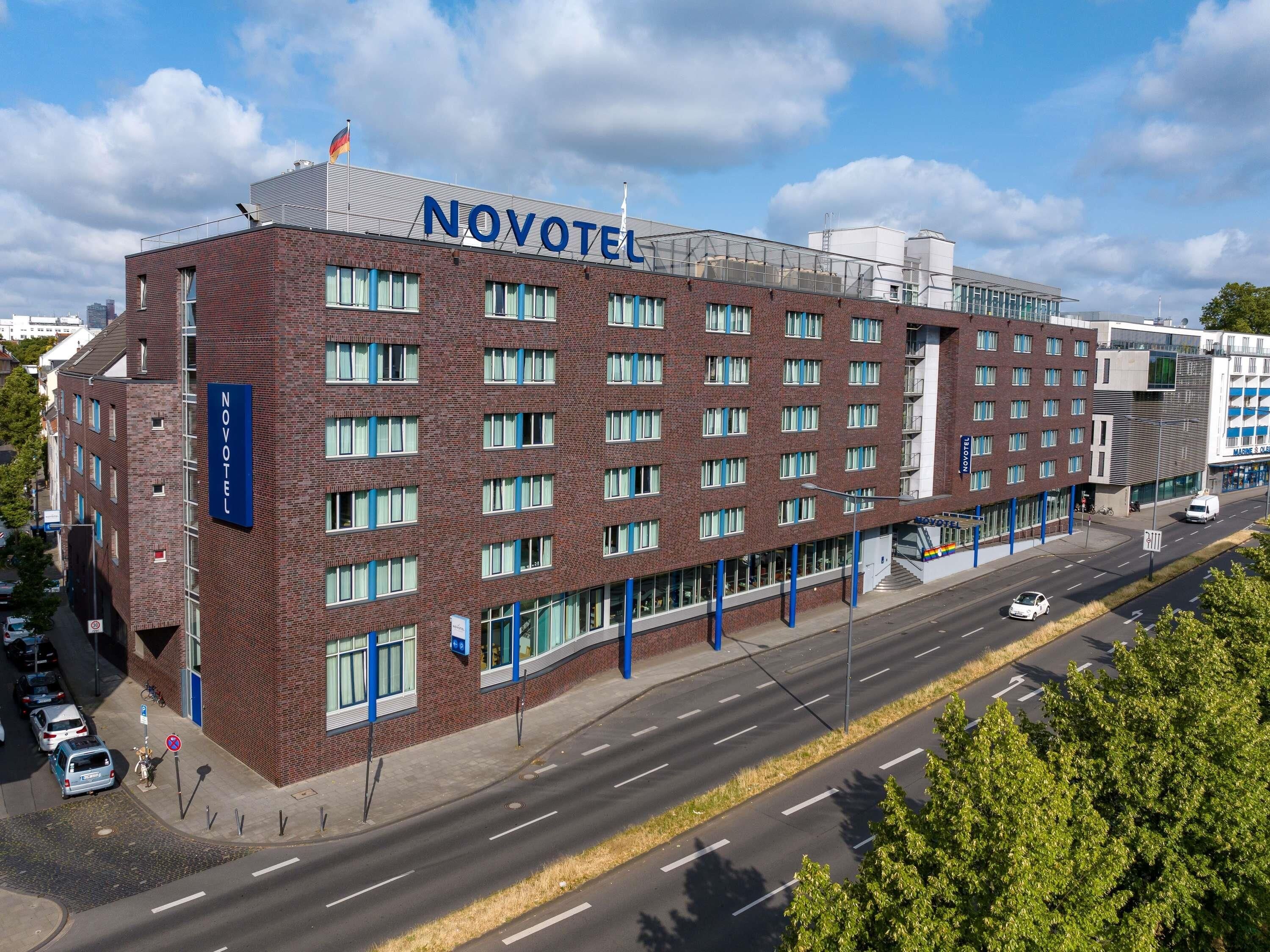 A multi-story hotel with a prominent 'NOVOTEL' sign, a brick facade, and a modern design.